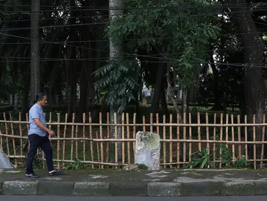 Warga melintas di samping pagar yang ambruk di Taman Hutan Tebet, Jakarta, Kamis (28/3). Kondisi pagar yang ambruk akibat hujan deras tersebut butuh perbaikan karena telah terabaikan selama beberapa bulan terakhir. (Liputan6.com/Immanuel Antonius)