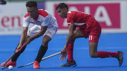 Asrul Alam dari Indonesia (kiri) memukul bola melawan pemain Singapura Ramanan Thulasiram, selama pertandingan hoki putradi Pesta Olahraga Asia Tenggara ke-32 di Phnom Penh, Kamboja, Selasa (9/5/2023). (AP Photo/Tatan Syuflana)