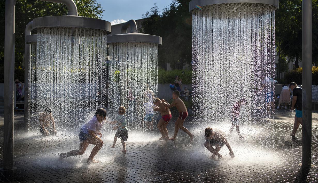 Anak-anak mendinginkan diri di air mancur umum di Vilnius, Lithuania, 26 Juni 2022. Gelombang panas berlanjut di Lithuania saat suhu naik hingga 32 derajat Celcius (89,6 derajat Fahrenheit). (AP Photo/Mindaugas Kulbis)