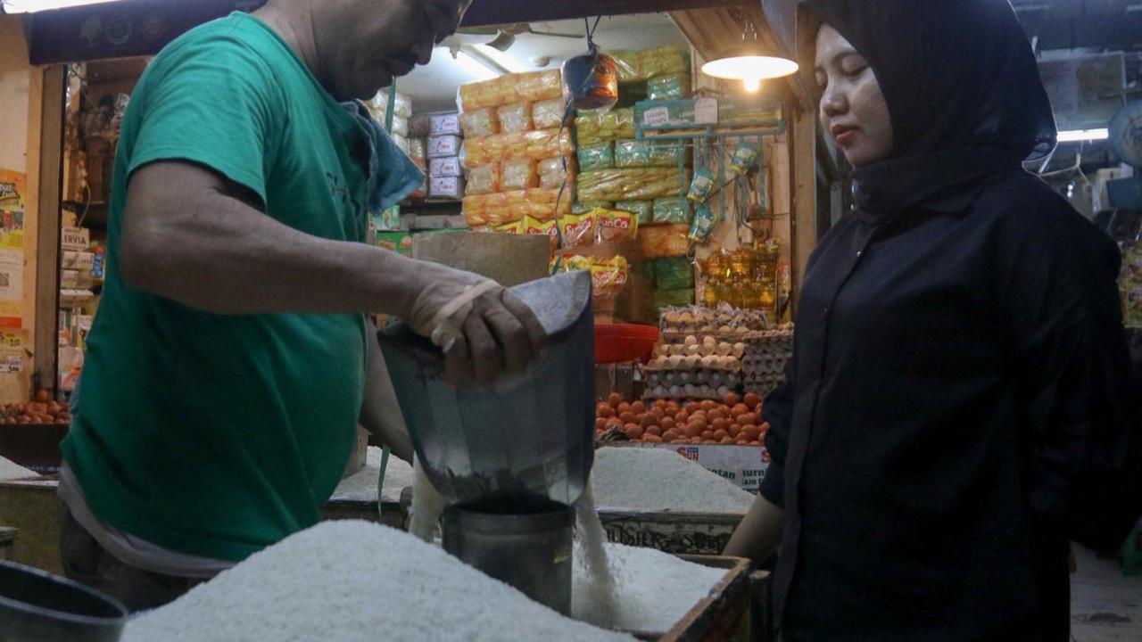 Pedagang beras sedang melayani pembeli bahan pokok tersebut di tengah harga beras yang melonjak tajam di Pasar Cibubur, Jakarta, Senin (19/2/2024). Foto: Liputan6.com / Herman Zakharia.