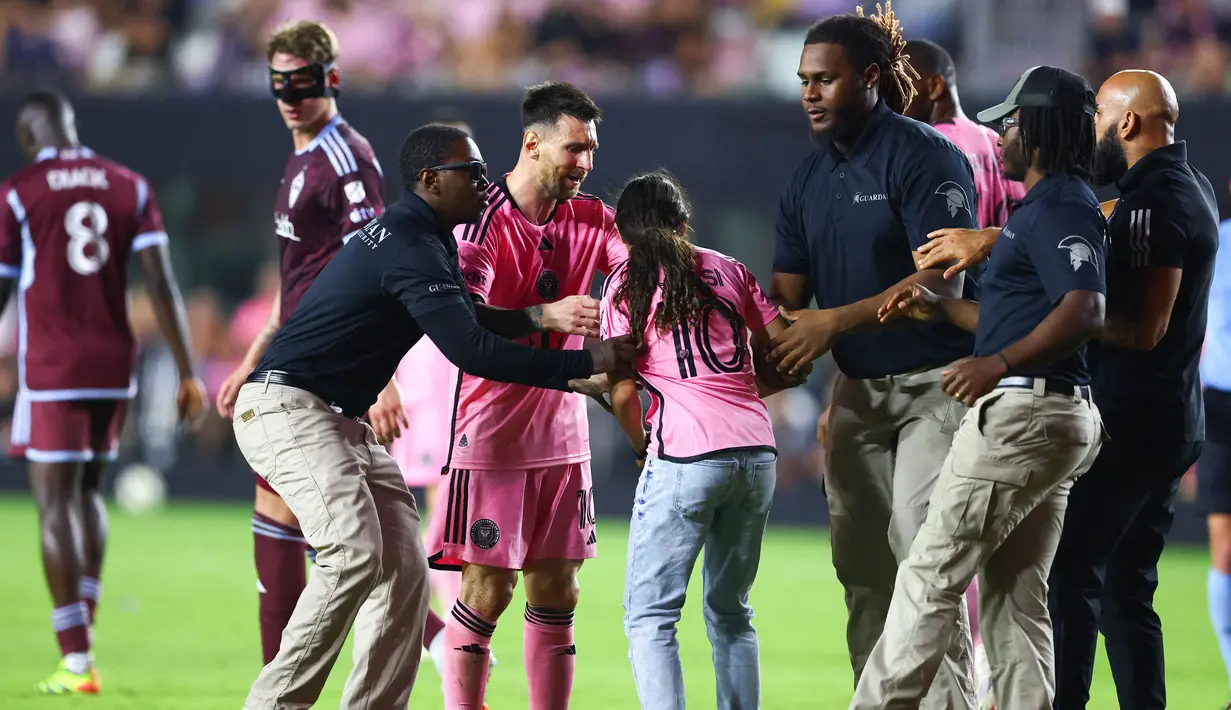 Seorang gadis diamankan oleh petugas keamanan setelah memasuki lapangan untuk berswafoto dengan Lionel Messi pada laga lanjutan Major League Soccer (MLS) antara Inter Miami melawan Colorado Rapids di Fort Lauderdale, Florida, Amerika Serikat, Minggu (07/04/2024) WIB. (AFP/Megan Briggs)