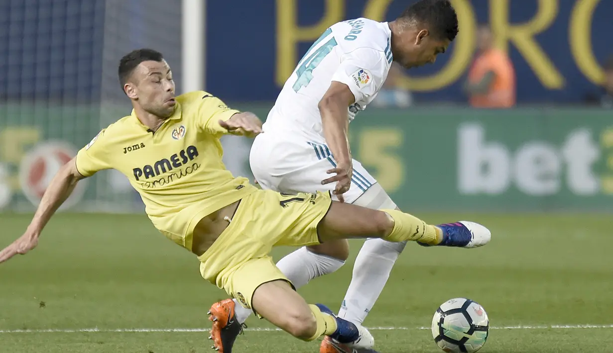 Pemain Villarreal, Javi fuego (kiri) berebut bola dengan pemain Real Madrid, Casemiro pada laga terakhir La Liga di Ceramica stadium, Villarreal, (19/5/2018). Real Madrid ber,min imbang 2-2. (AFP/Jose Jordan)