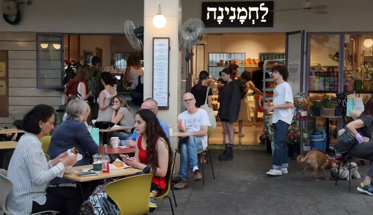 Orang-orang menikmati makanan di kafe di Abima Square di kota Tel Aviv, Israel (20/5/2021). Israel dan dua kelompok bersenjata utama Palestina di Gaza, Hamas dan Jihad Islam, menyetujui gencatan senjata untuk mengakhiri konflik selama 11 hari. (AFP/Gideon Markowicz)