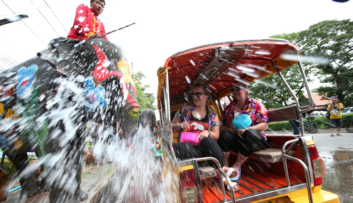 Seorang pawang menunggang gajah yang menyemprotkan air kepada wisatawan saat perayaan tahun baru kuno Thailand atau Songkran di provinsi Ayutthaya, Thailand (11/4). Songkran merupakan salah satu perayaan Tahun Baru Thailand. (AP Photo/Sakchai Lalit)