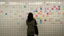 Seorang wanita menempelkan post-it sebagai bagian dari 'subway therapy' di dinding stasiun Union Square, New York, Kamis (10/11). Subway therapy digunakan kaum komuter yang kesal dan kecewa terpilihnya Donald Trump sebagai Presiden AS. (DREW ANGERER/AFP)