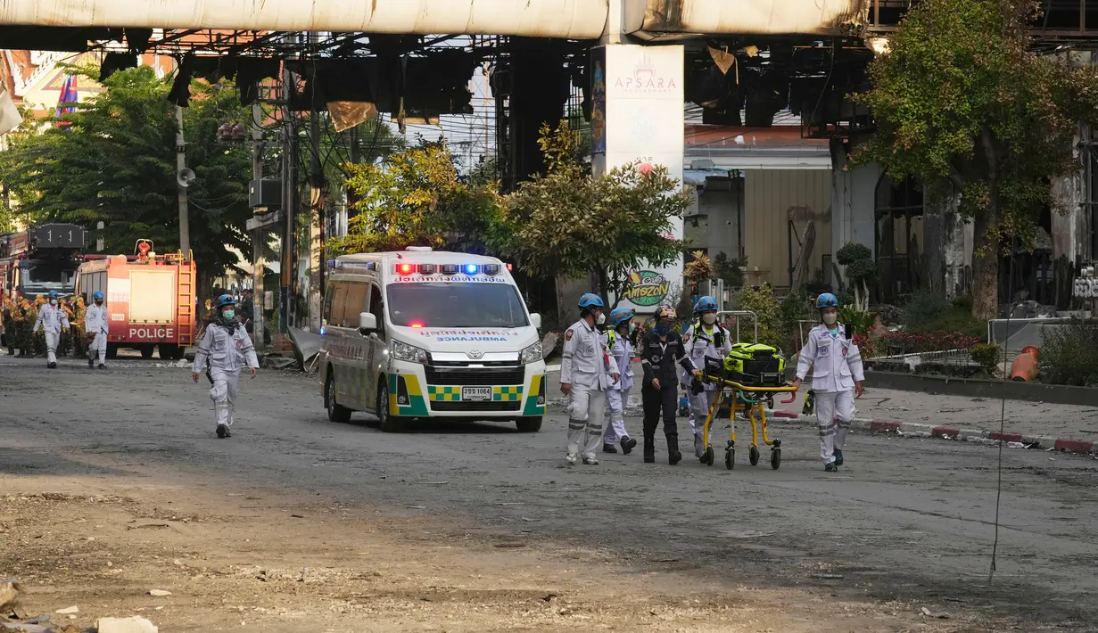 Pakar penyelamat Kamboja dan Thailand berjalan melalui reruntuhan bangunan di lokasi kebakaran besar kasino hotel Kamboja di Poipet, Kamboja, Jumat (30/12/2022). Dalam laporan sementara polisi Kamboja, ada 30 orang terluka akibat kebakaran itu. (AP Photo/Heng Sinith)