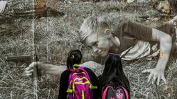 Dua anak sekolah melihat foto jurnalistik karya Sara Blesener, Kolombia (1/11). Karya ini diprakarsai oleh Dysturb, sebuah komunitas jurnalis foto yang berkeinginan membuat informasi visual secara bebas diakses oleh khalayak luas. (AFP PHOTO/luis acosta)