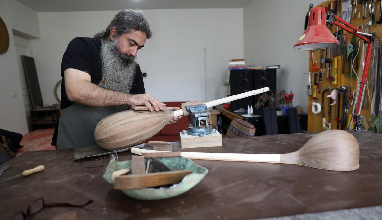 Luthier Ali Akbar Soleimani mengamplas alat musik petik bernama Tanbur yang sedang dibuat di bengkel kerjanya di Teheran, Iran pada 28 Januari 2021. Tanbur merupakan alat musik dawai berleher panjang yang berasal dari kawasan Mesopotamia, Asia Selatan atau Tengah. (AP Photo/Vahid Salemi)