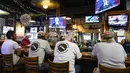 Sejumlah pria duduk di bar sementara Presiden Joe Biden menyampaikan pidato pelantikannya di televisi di belakang bar, di Ferg's Sports Bar di St. Petersburg, Florida (20/1/2021).  Joe Biden menjadi presiden AS tertua dalam sejarah. (Martha Asencio Rhine/Tampa Bay Times via AP)