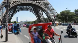 Wisatawan berkeliling kota Paris menggunakan transportasi becak, Prancis, (7/7). Menurut media setempat, kemunculan becak ini membuat para sopir taksi memiliki saingan. (AFP Photo/Jacques Demarthon)
