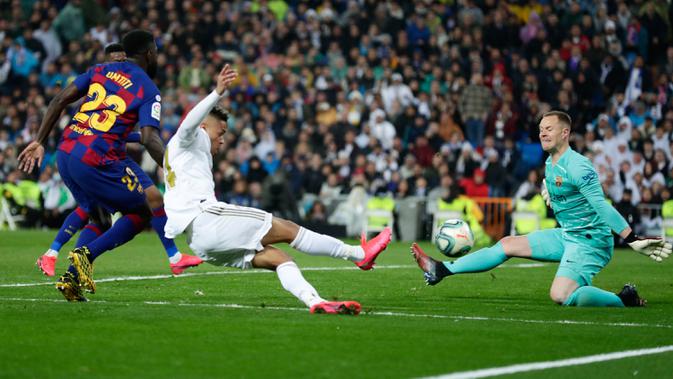Penyerang Real Madrid, Mariano Diaz (tengah) mencetak gol melewati kiper Barcelona, Marc-Andre ter Stegen pada lanjutan pertandingan La Liga di Santiago Bernabeu, Minggu (2/3/2020). Real Madrid membungkam Barcelona 2-0 dan merebut puncak klasemen dari Barcelona . (AP/Manu Fernandez)