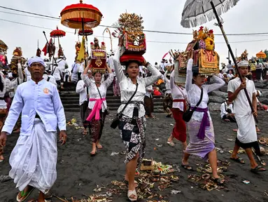 Umat Hindu berjalan untuk berdoa sambil membawa persembahan saat upacara Melasti di sebuah pantai di Denpasar, Bali, pada Rabu 26 Maret 2025. (Sonny TUMBELAKA/AFP)