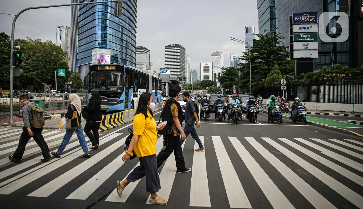 Sejumlah pekerja berjalan melintas pelican cross di kawasan Jalan Sudirman, Jakarta, Selasa (2/11/2021). Sektor non-esensial kini boleh mempekerjakan hingga 75 persen karyawannya dari kantor. Sebelumnya, angka ini dibatasi hingga 50 persen. (Liputan6.com/Faizal Fanani)