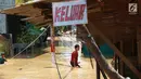 Anak-anak melintasi banjir yang menggenangi kawasan Pejaten Timur, Jakarta, Jumat (26/4). Banjir yang berasal dari luapan Sungai Ciliwung tersebut merendam ratusan rumah warga hingga kedalaman lebih dari satu meter. (Liputan6.com/Immanuel Antonius)