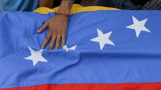 Bendera negara Venezuela yang bawa saat mengiringi pemakaman Jose Francisco Guerrero di San Cristobal, Tachira State, Venezuela (19/5). Jose tewas akibat tembakan saat ia terjebak dalam konfrontasi antara demonstran dan polisi setempat. (AFP/Luis Robayo)