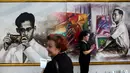 Warga yang melayat berdiri di depan gambar raja Thailand Bhumibol Adulyadej di dekat Grand Palace, Bangkok, Selasa (18/10). Lukisan yang dibuat mahasiswa seni dipajang di dekat Grand Palace di Bangkok, Thailand (18/10). (Reuters/Athit Perawongmetha)