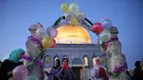 Wanita Muslim meniup balon saat jamaah merayakan hari raya Idul Fitri, yang menandai akhir bulan suci Ramadhan, setelah sholat subuh di kompleks masjid Al-Aqsa, dengan latar belakang masjid Kubah Bat  di Yerusalem Tua (13/5/2021). (AFP/Ahmad Gharabli)
