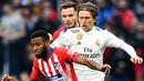 Gelandang Real Madrid, Luka Modric berusaha merebut bola yang dibawa gelandang Atletico Madrid, Thomas Lemar selama pertandingan lanjutan La Liga Spanyol di stadion Wanda Metropolitano (9/2). Real Madrid menang 3-1. (AFP Photo/Gabriel Bouys)