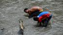 Dua pria mencari logam berharga di Sungai Guaire, di Caracas, Venezuela (1/2). Puluhan warga mencari logam atau tembaga setiap hari di Sungai Guaire, tempat selokan Caracas mengalir.  (AFP Photo/Federico Parra)