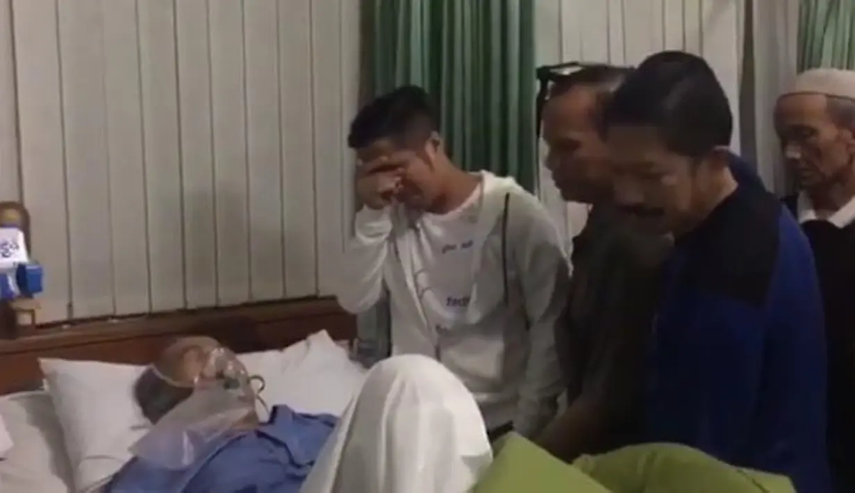 Melihat ayahnya yang berjuang melawan sakit kala itu, dengan bantuan alat pernapasan, Irfan pun tak kuasa menahan tangisnya. Di sisi sang ayah, Irfan bersama para penjenguk lainnya kala itu pun terlihat bersedih. (Instagram/irfanhakim75)