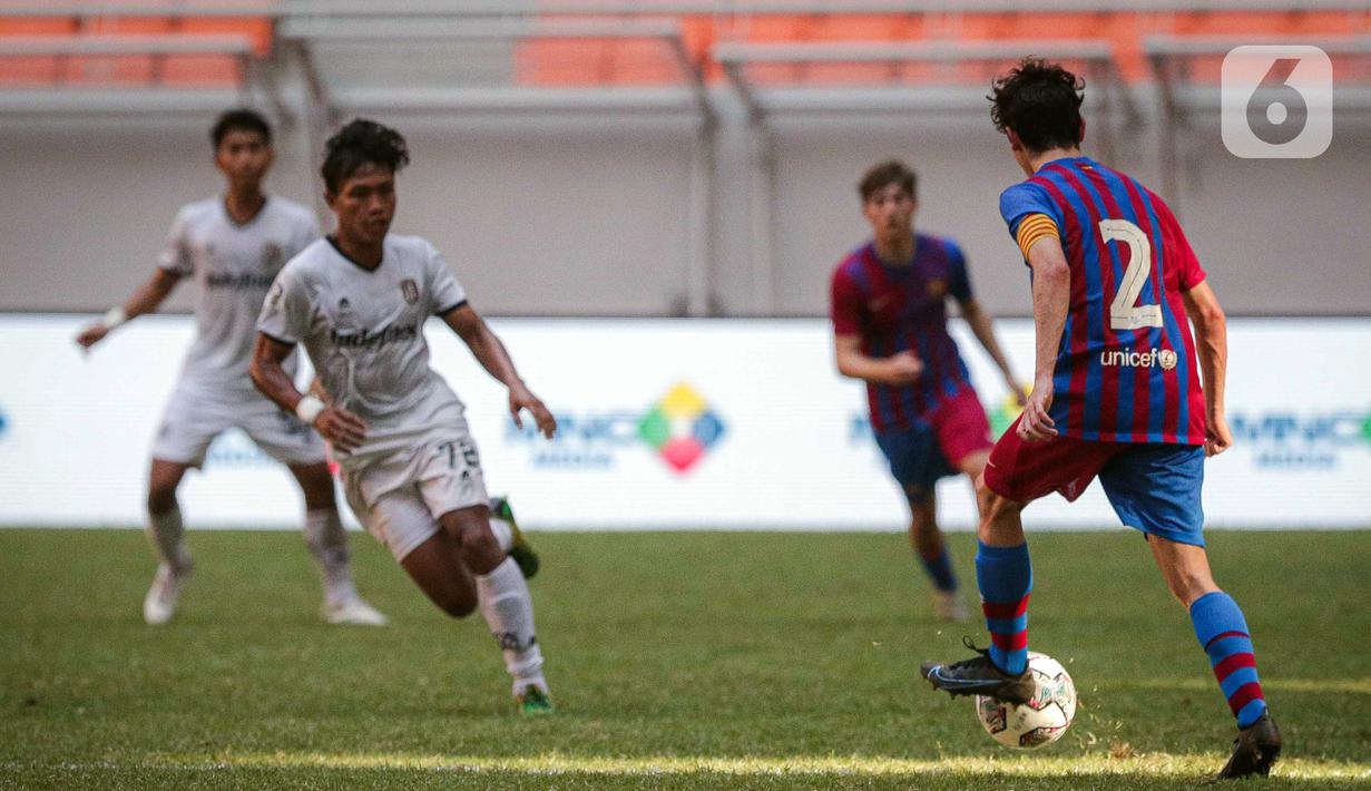 Pemain Barcelona U-18 Joan Anaya Balaña (kanan) mengontrol bola saat melawan Bali United U-18 pada pertandingan International Youth Championship (IYC) 2021 di Jakarta International Stadium (JIS), Jakarta, Minggu (17/4/2022). Barcelona U-18 menang 4-0. (Liputan6.com/Faizal Fanani)