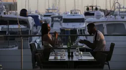 Sepasang suami istri duduk di sebuah restoran di tepi marina di Vilamoura, Algarve, Portugal, Senin (17/5/2021). Wisatawan Inggris mulai berdatangan dalam jumlah besar di selatan Portugal setelah pemerintah di kedua negara melonggarkan pembatasan perjalanan pandemi COVID-19. (AP Photo/Ana Brigida)