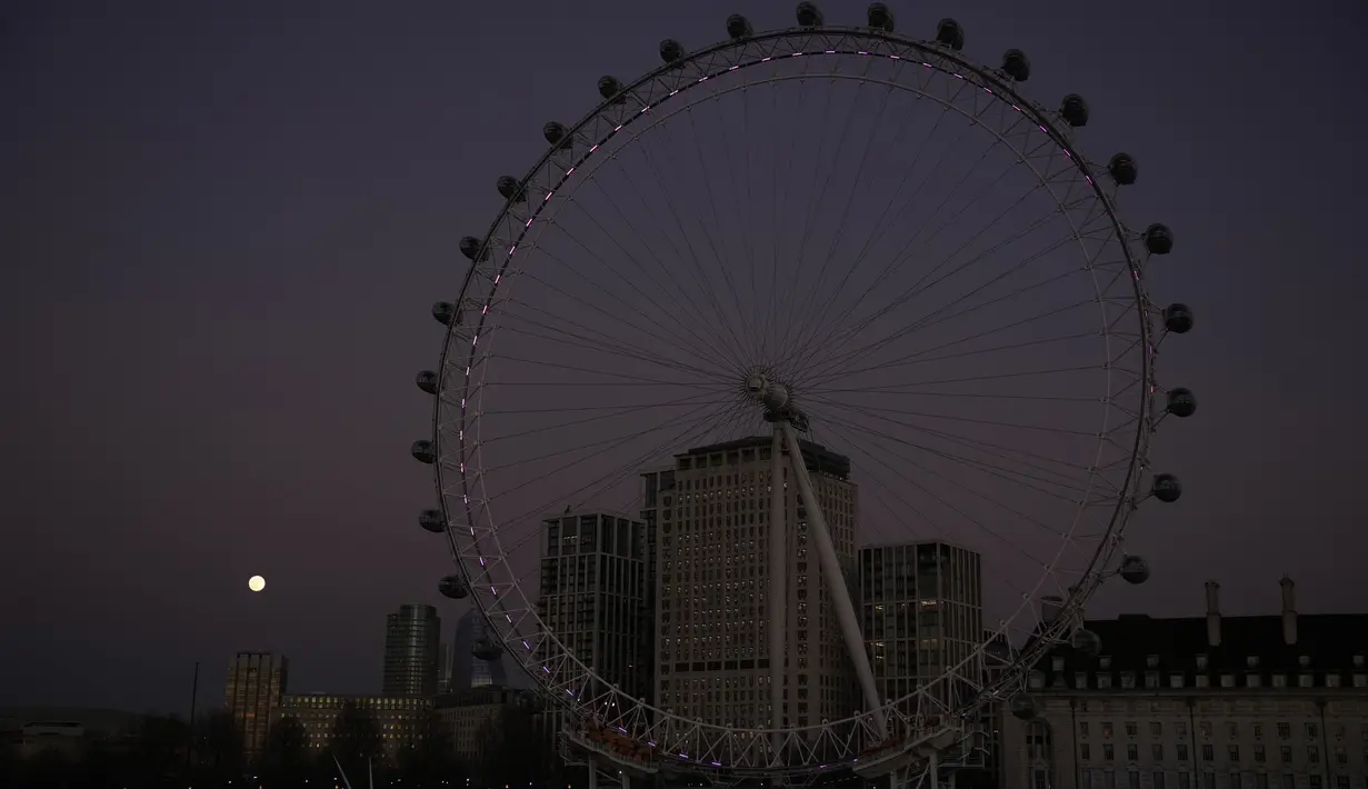 Bulan purnama pertama tahun yang dikenal sebagai Wolf Moon terlihat di belakang London Eye ferris Wheel, di London, Senin (17/1/2022). Wolf Moon atau disebut juga Bulan purnama Serigala adalah sebutan untuk bulan purnama pertama di Januari. (AP Photo/Matt Dunham)