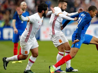 Penyerang Prancis, Kylian Mbappe (kanan) berusaha membawa bola dari kejaran dua pemain Spanyol Isco dan Jordi Alba pada laga persahabatan di Paris, (29/3). Spanyol menang atas Prancis dengan skor 2-0. (AP Photo / Christophe Ena)