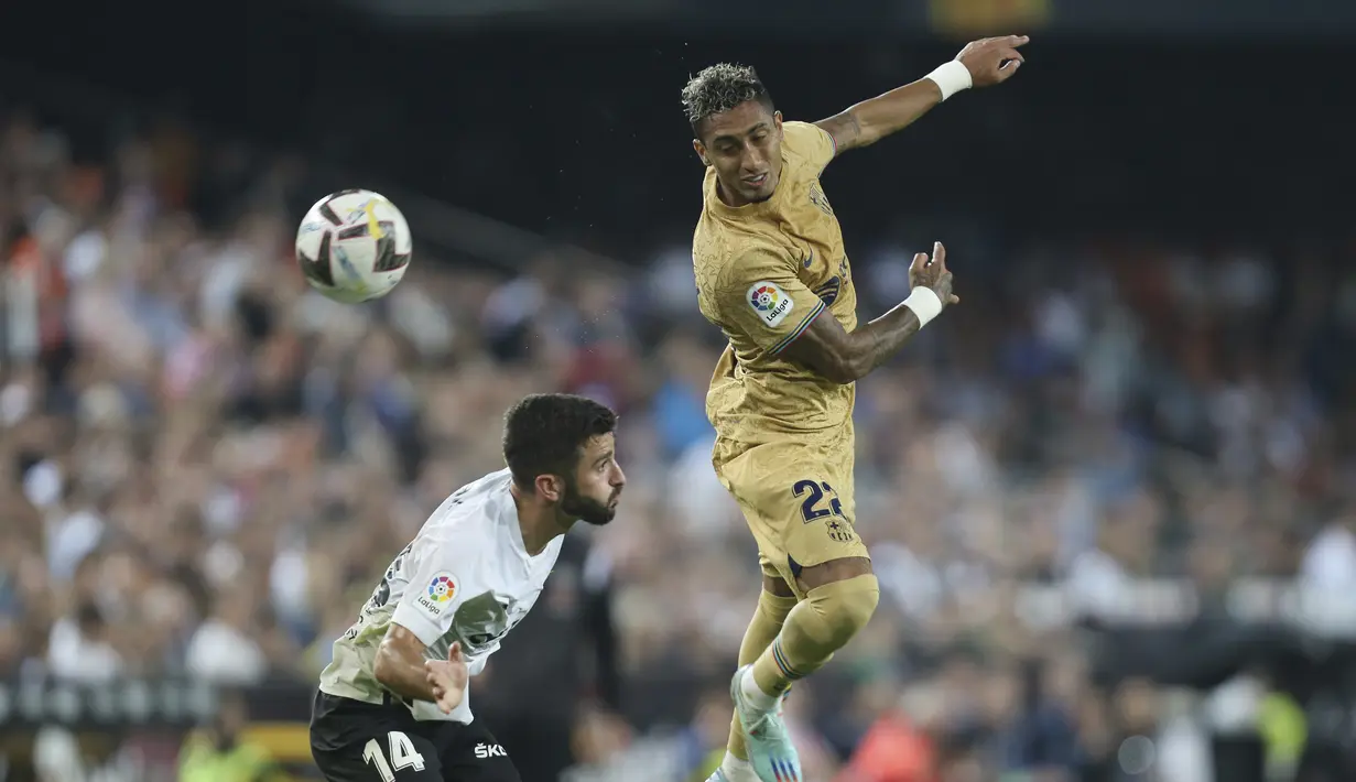 Penyerang Barcelona Raphinha melompat untuk meyundul bola melewati bek  Valencia Jose Gaya pada jornada ke-12 La Liga 2022/23 di Mestalla, Minggu (30/10/2022) dini hari WIB. Sementara Valencia harus puas berada di peringkat 10 dengan koleksi 15 poin dari 12 laga. (AP Photo/Alberto Saiz)