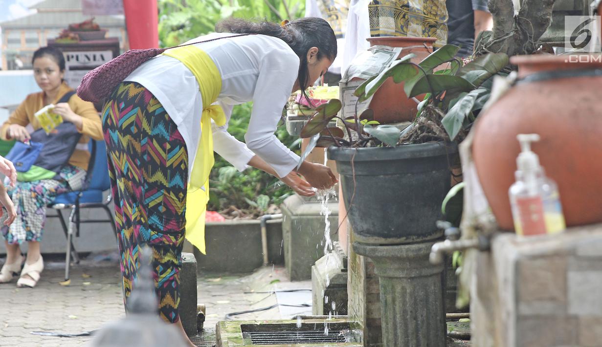 Umat Hindu mengambil air suci sebelum memasuki Pura Aditya Jaya, Jakarta, Sabtu (17/3). Pura Aditya Jaya menjadi tempat perayaan Nyepi umat Hindu di Jakarta. (Liputan6.com/Herman Zakharia)