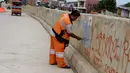 Petugas Pekerja Penanganan Sarana dan Prasarana Umum (PPSU) mengecat tembok yang penuh dengan vandalisme di sepanjang sisi tanggul Kali Ciliwung, Jakarta, Selasa (11/10). (Liputan6.com/Gempur M Surya)