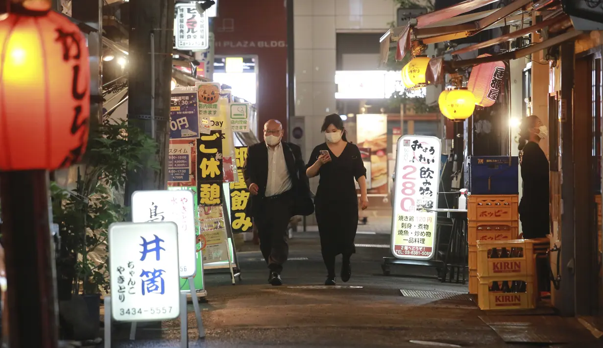 Orang-orang melintasi jalan di Tokyo, Jepang, Senin (25/10/2021). Orang-orang di Tokyo dapat makan dan minum di bar dan restoran mulai Senin malam ketika aturan jarak sosial dilonggarkan karena kasus COVID-19 harian di negara itu mencapai level terendah dalam setahun lebih. (AP Photo/Koji Sasahara)