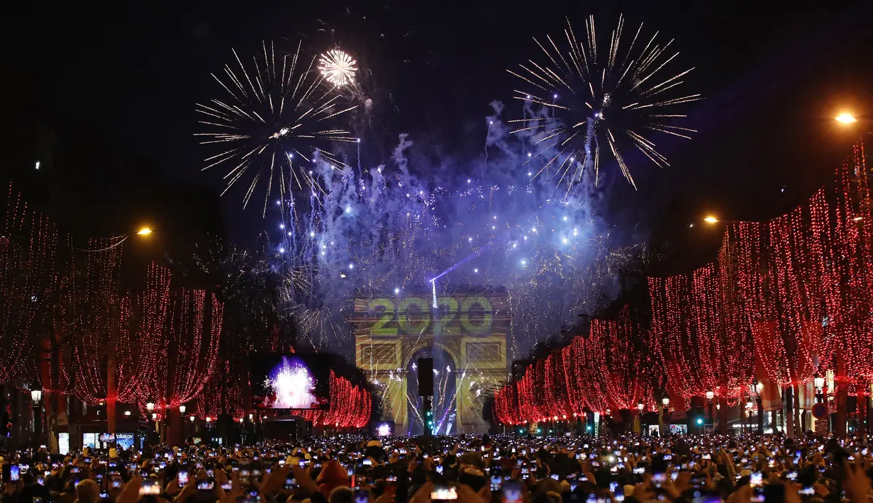 Sejumlah warga memotret kembang api di atas Arc de Triomphe ketika mereka merayakan Tahun Baru di Champs Elysees, di Paris, Prancis, Rabu (1/1/2019). (AP Photo / Christophe Ena)