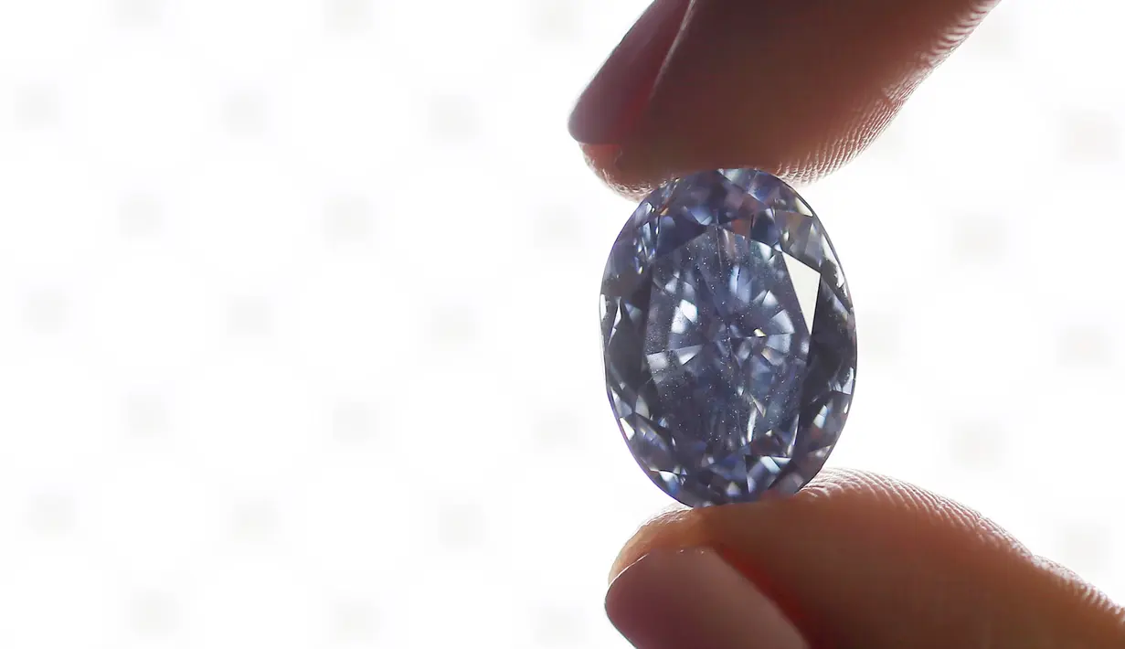 Seorang petugas memegang berlian biru 10,10 karat di rumah lelang sothbey, London, Inggris, Selasa (15/3). Diperkirakan harga berlian ini mencapai $ 35.000.000 atau 525 Miliar rupiah.  (REUTERS / Stefan Wermuth)