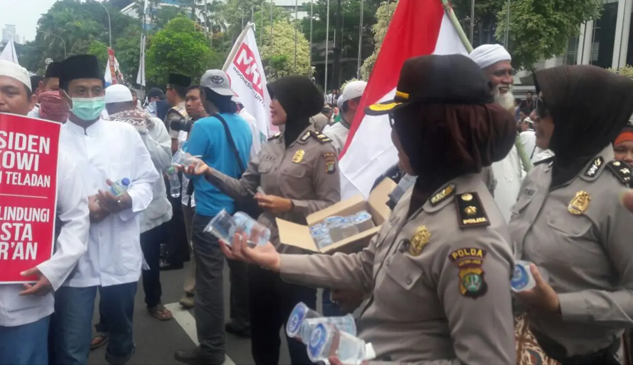 Sejumlah polwan memberikan minuman kepada pengunjuk rasa saat Aksi Damai 4 November di Jakarta, Jumat (4/11). Hampir semua polwan yang berjaga dalam aksi ini mengenakan hijab. (Twitter.com/@hidcom)