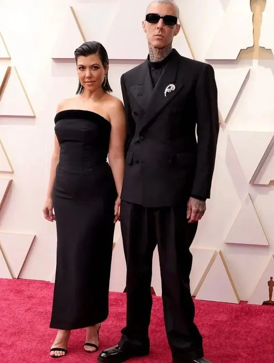 Kourtney Kardashian hadir di Oscar 2022 bersama sang tunangan, Travis Barker. Pasangan ini terlihat serasi kenakan busana all black.  Kourtney kenakan dress dari Tab Vintage, sementara Travis kenakan tuksedo dari Maison Margiela. (Instagram/ fashionbombdaily).