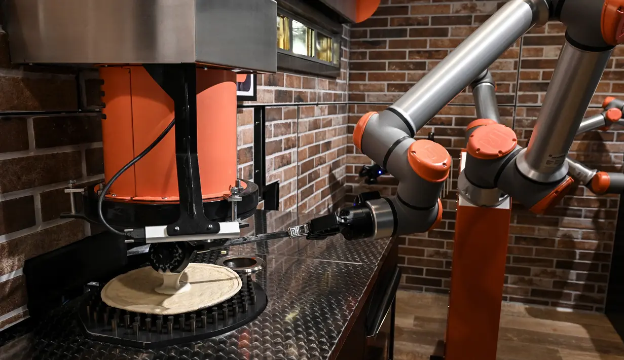 Robot pembuat pizza Bernama "Pazzi" terlihat sedang bekerja di sebuah restoran di Paris pada 1 Juli 2021. Pazzi dapat menjadi cikal bakal pasukan robot koki masa depan di seluruh dunia. (BERTRAND GUAY/AFP)