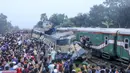 Orang-orang berkumpul di dekat gerbong kereta yang rusak parah setelah dua kereta yang melaju bertabrakan di distrik Brahmanbaria, 82 kilometer (51 mil) timur ibukota, Dhaka, Bangladesh, Selasa (12/11/2019). Sekitar 16 orang tewas dan 60 lainnya terluka akibat kecelakaan tersebut. (AFP Photo/STR)