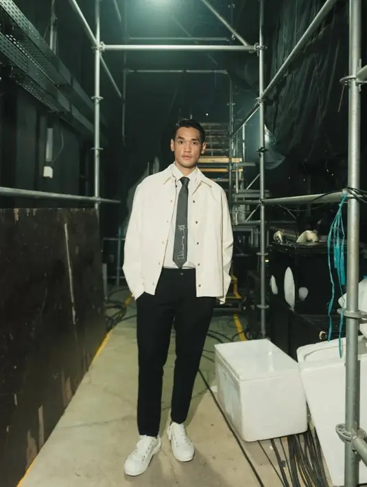 Preppy look dari Afgan. Ia mengenakan kemeja lengkap dengan dasi panjangnya, ditumpuk dengan structured outer berwarna putih yang senada, dipadukan dengan celana panjang hitam, dan sneakers putih. [Foto: Instagram/afganisme.official]