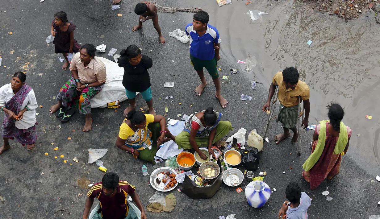 Warga pengungsi memasak makanan mereka di pinggir jalan banjir di Chennai, India, (3/11/2015). Curah hujan terparah dari satu abad telah menyebabkan banjir besar di seluruh negara bagian India Tamil Nadu. (REUTERS/Anindito Mukherjee)