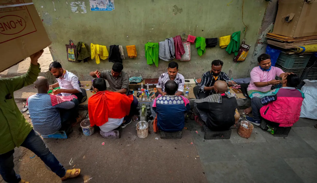 Tukang cukur melayani pelanggan di trotoar di sebuah pasar grosir sayuran di Guwahati, India, Rabu (1/2/2023). Pemerintah Perdana Menteri India Narendra Modi berencana meningkatkan belanja modal sebesar 33% menjadi $122 miliar dalam anggaran tahunan yang diajukan ke Parlemen untuk memacu pertumbuhan ekonomi dan menciptakan lapangan kerja menjelang pemilihan umum tahun depan. (AP Photo/Anupam Nath)