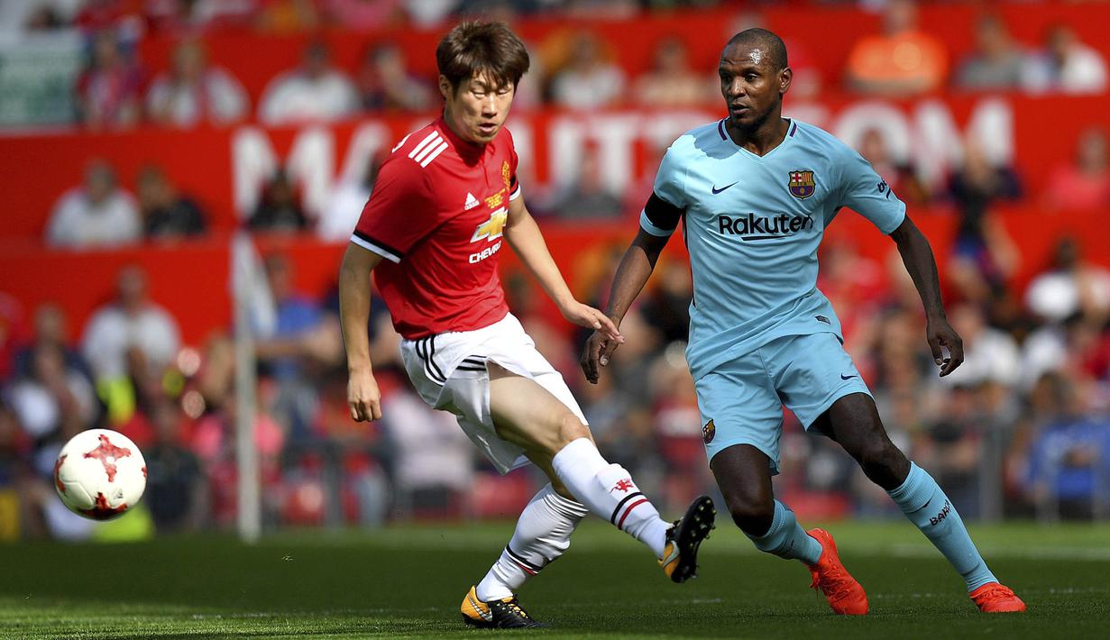 Legenda Manchester United, Ji-Sung Park, berebut bola dengan legenda Barcelona, Eric Abidal, di Stadion Old Trafford, Sabtu (2/9/2017). Pertandingan tersebut merupakan laga amal. (AP/Dave Howarth)