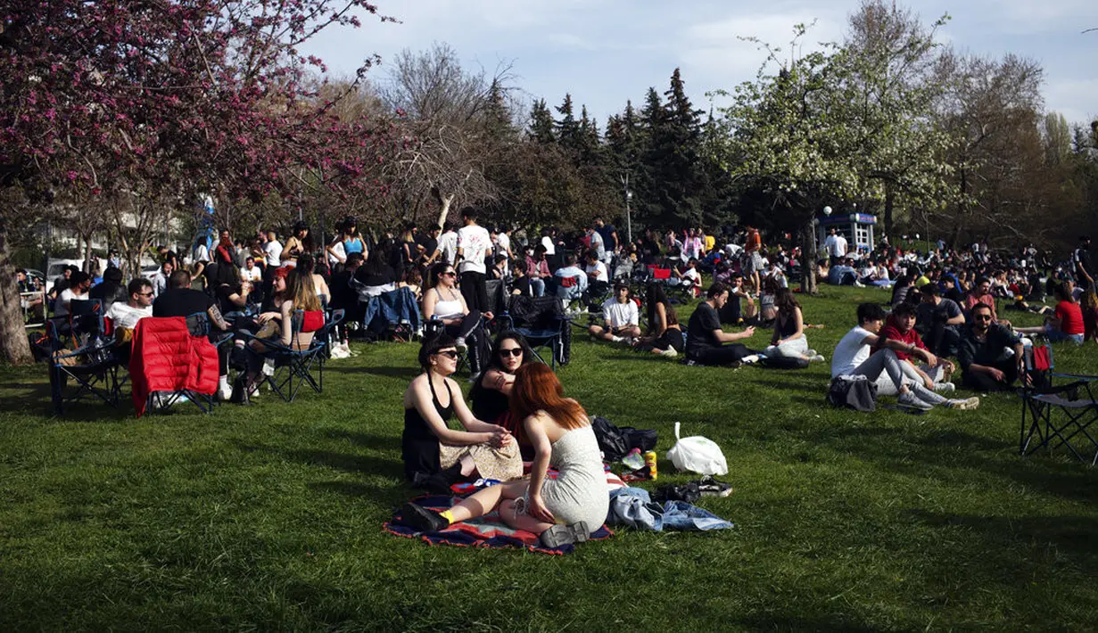 Orang-orang duduk di sebuah taman di Ankara, sehari sebelum penerapan "penguncian penuh" atau lockdown, Rabu (28/4/2021). Turki akan memberlakukan lockdown penuh selama tiga minggu dari 29 April hingga 17 Mei 2021 untuk membendung penyebaran virus corona. (AP Photo/Burhan Ozbilici)