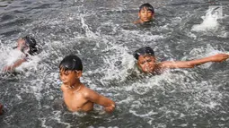 Anak-anak berenang di Kanal Banjir Barat (KBB) yang hitam di Petamburan, Jakarta, Senin (12/8/2019). Anak-anak memanfaatkan waktu pulang sekolah mereka untuk berenang dan mencari ikan di KBB saat musim kemarau. (Liputan6.com/Fery Pradolo)