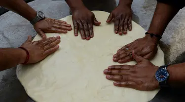 Koki India menyiapkan adonan untuk membuat roti goreng yang dikenal dengan sebutan Bhatura, India, New Delhi, Kamis (6/4). Penyelenggara berharap Bhatura buatan mereka bisa memecahkan rekor Bhatura  terbesar di India. (AFP PHOTO / SAJJAD HUSSAIN)