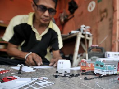 Iskandar (52) saat menyelesaikan pembuatan miniatur kereta api di kawasan Manggarai, Jakarta, Kamis (21/11/2019). Sudah 6 tahun bapak dari 2 anak ini menekuni profesi sebagai pembuat miniatur kereta api berbagai jenis, mulai dari KRL, kereta jarak jauh, hingga MRT. (merdeka.com/Iqbal S. Nugroho)