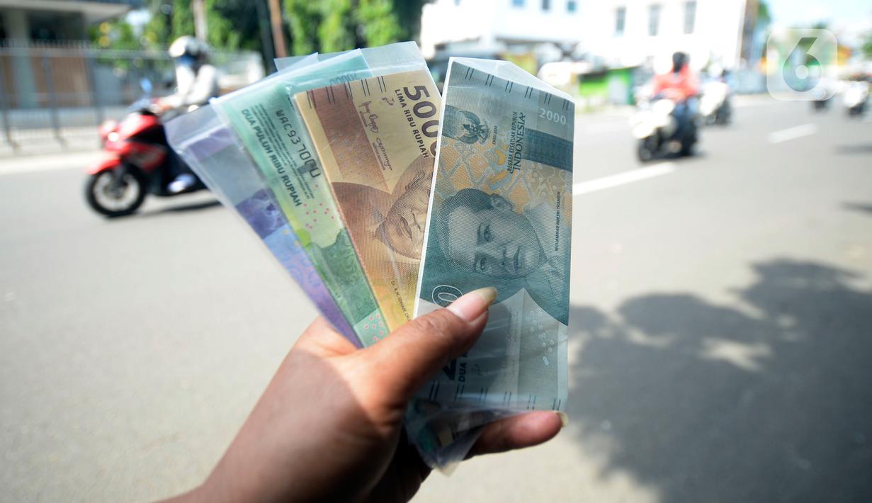 Penjual jasa penukaran uang menawarkan uang baru berbagai pecahan kepada pengguna jalan di kawasan Bintaro Sektor 2, Jakarta Selatan, Selasa (12/05/2020). Pembeli uang kertas baru yang biasanya ramai menjelang Lebaran, kini sepi di tengah pandemi virus corona Covid-19. (merdeka.com/Dwi Narwoko)