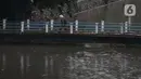 Warga melintasi jembatan penyeberangan kali di  kawasan Kuningan, Jakarta, Kamis (18/12/2021). BMKG memprakirakan potensi hujan lebat yang mungkin disertai petir dan angin kencang hingga 21 Februari di beberapa provinsi di Indonesia, termasuk DKI Jakarta. (Liputan6.com/Helmi Fithriansyah)