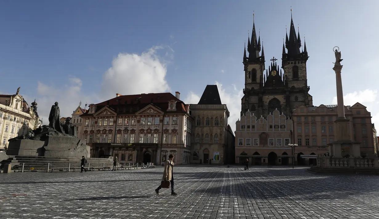 Warga berjalan-jalan di Alun-alun Kota Tua di Praha di mana ribuan salib dilukis untuk menandai satu tahun sejak kematian pertama akibat Covid-19 di Republik Ceko, Senin (22/3/2021). Sekelompok aktivis melukis salib untuk mengkritik tanggapan pemerintah terhadap pandemi corona. (AP/Petr David Josek)