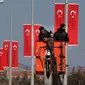 Buruh memasang bendera di tiang listrik menuju perbatasan Oncupinar di Kota Kilis, Turki, Senin (29/1). Bentrokan sempat meletus di puncak bukit strategis di Suriah karena milisi Kurdi mencoba mendapatkan kembali kontrol. (AP Photo/Lefteris Pitarakis)